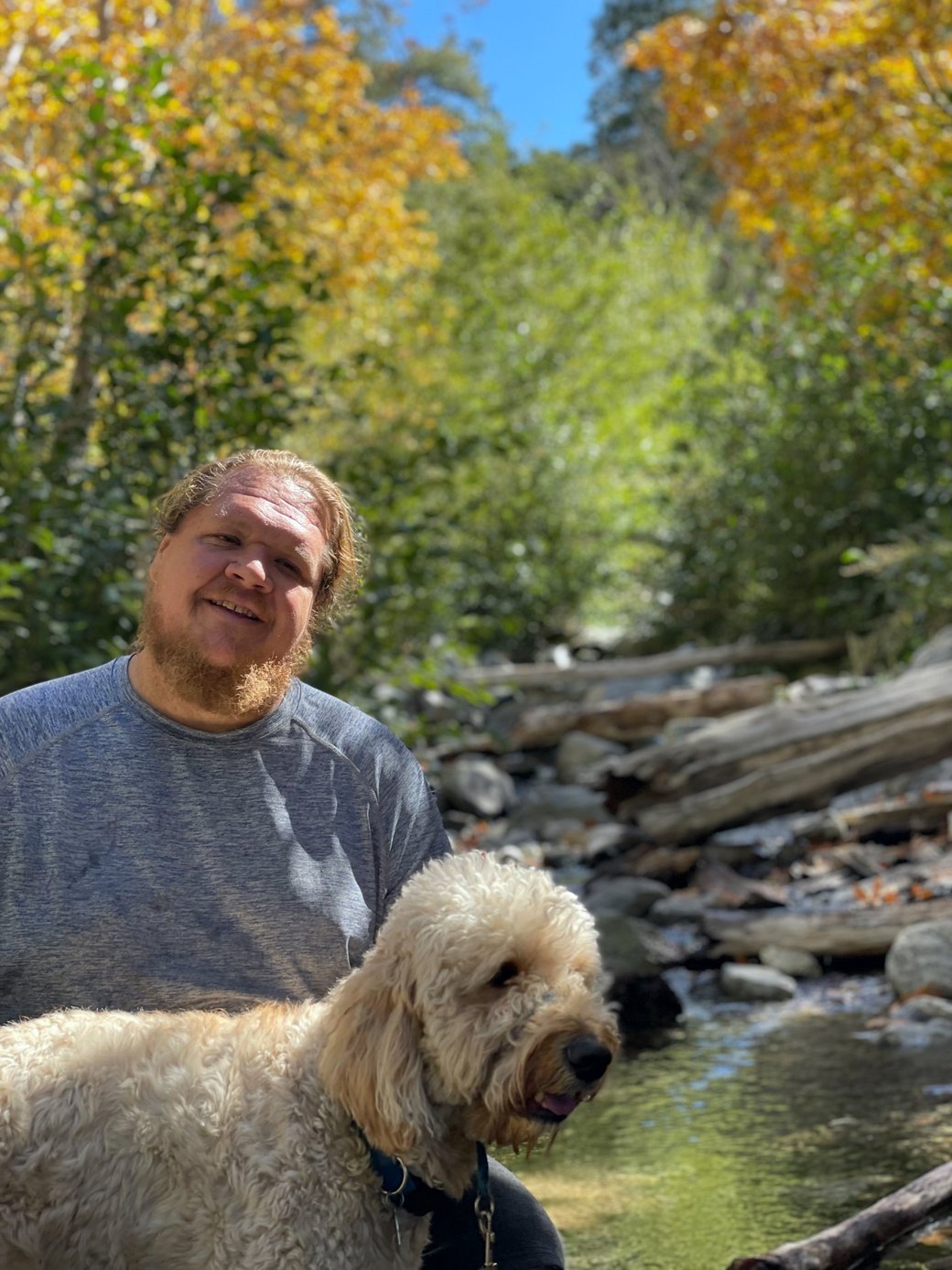 Troy, the founder of PonyBox, outdoors by a creek with his dog